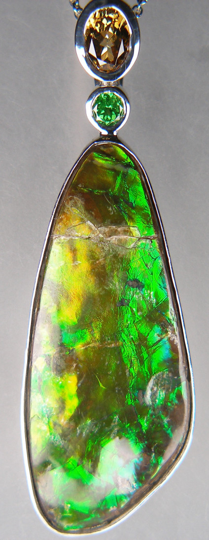Ammolite, chrysoberyl & green garnet pendant in silver - Striking and impressive pendant with 28.21ct ammolite from Alberta, Canada, set with a 1.38ct oval golden yellow chrysoberyl and 0.33ct round green tsavorite garnet, all gems rubover set in silver. The pendant measures 62x22mm. The chain is available for separate purchase.