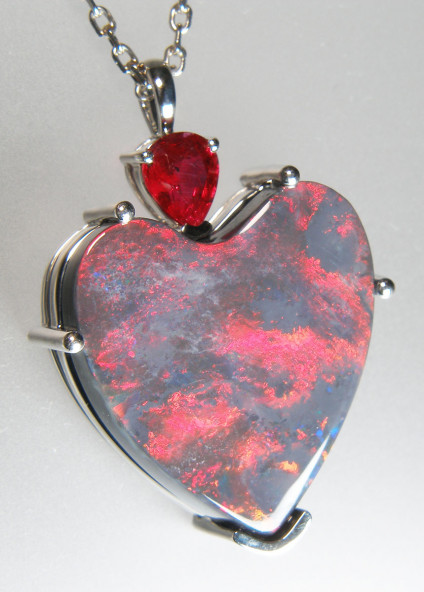 Black opal & ruby pendant in platinum - Fiery red black opal heart weighing 10.29ct. This opal is from Lightning Ridge, New South Wales, Australia and is exceptionally rare. It is set below a vibrant Ruby pear cut weighing 0.8ct. Bothe stones are mounted in platinum. The chain is not included in the price.