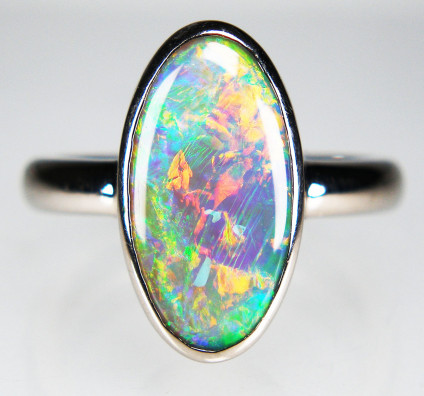 Dark crystal opal ring in 18ct white gold - 3.32ct oval cabochon dark crystal opal from the CorcoranOpal field near Lightning Ridge, New South Wales, rubover set in 18ct white gold ring. 
