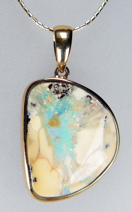 Boulder opal pendant in 9ct yellow gold - Fascinating cream and turquoise coloured polished boulder opal pendant rubover set in 9ct yellow gold. Pendant measures 35 x 20mm. Chain is not included.