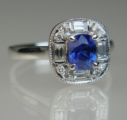 Sapphire & diamond deco style ring in 18ct white gold - Cushion cut blue sapphire 1.03ct (6x5x3.8mm) set with four baguette cut and 8 round brilliant cut white diamonds totalling 0.31ct in 18ct white gold. This ring is designed to fit against a wedding band. The ring size is N, although our expert goldsmiths can resize this ring to fit your finger as required.