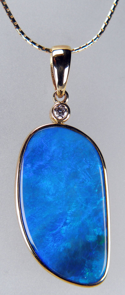 Boulder opal & diamond pendant in 9ct yellow gold - Boulder opal pendant in vivid kingfisher blues rubover set in 9ct yellow gold with a 0.08ct diamond accent. Pendant measures 40 x 16mm. Price excludes chain.