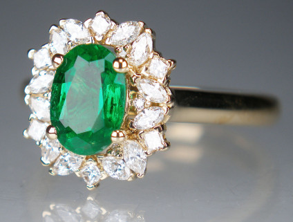 Emerald & diamond ring in 18ct yellow gold - 7x5mm oval emerald set with an assortment of round brilliant cut, princess cut and marquise cut diamonds in 18ct yellow gold