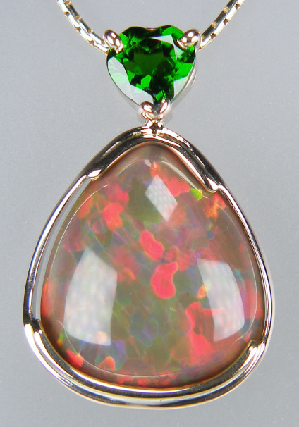 Ethiopian opal & chrome diopside pendant in 9ct yellow gold - Spectacular multi-coloured Ethiopian opal pear shaped cabochon set with a heart cut green chrome diopside in 9ct yellow gold and suspended from an 18" 9ct yellow gold anaconda style chain. Pendant is 27 x 18mm. The chain is not included in the price and is available for separate purchase.