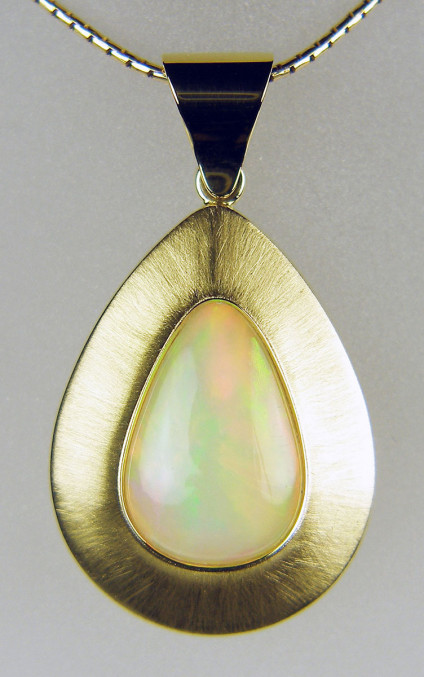 Ethiopian opal pendant - 8.52ct Ethiopian opal pear shaped cabochon set in brushed and polished 18ct yellow gold handmade mount and suspended from 18" 18ct yellow gold cable. The pendant is 40mm long and 23 mm wide. The opal flashes spectacular orange, pink and green colours. The pendant was designed by Helen Plumb and handmade for Just Gems by Martin MacGregor of Kinross.