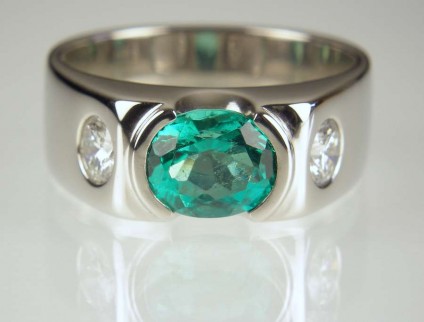 Emerald & diamond ring in palladium - 1.01ct oval Colombian emerald rubover set with a pair of 25pt each stone round brilliant cut diamonds in palladium. Customer's own diamonds.
