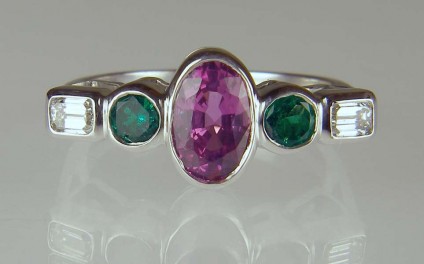 Pink sapphire, emerald & diamond ring - 1.63ct oval pink sapphire (independently certified as natural and unheated), set with 0.4ct pair of round cut Colombian emeralds and 0.30ct emerald cut diamond pair F colour SI1 clarity, in 18ct white gold