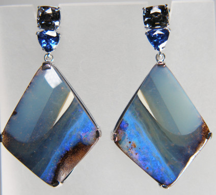 Boulder opal, sapphire & grey spinel earrings in 9ct white gold - Grey, white and blue boulder opal diamond shaped matched pair weighing 39.10ct from Queensland, Australia, claw set below a pretty trillion cut pair of blue sapphires weighing 0.92ct and a pair of cushion cut grey spinels from Myanmar weighing 1.49ct. The earrings are 40mm long and 22mm wide. These earrings are designed and made by Just Gems and are hallmarked in Edinburgh. 