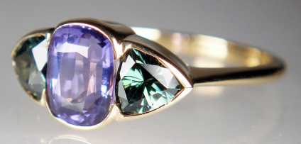 Teal & purple sapphire ring in 18ct yellow gold - Cushion cut 2.10ct purple sapphire flanked by a 1.15ct pair of trillion cut blue/green coloured sapphires, rubover set in 18ct yellow gold ring