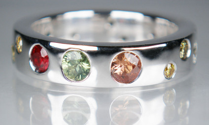 Multistone ring in 9ct white gold - 5mm wide 9ct white gold ring set with an assortment of round brilliant cut sapphires, diamonds and a ruby
