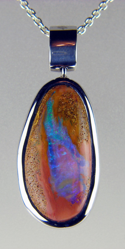 Wood opal pendant in silver - There is a vivid turquoise streak of wood opal, a colour in startling contrast to the sandstone matrix in this oval pendant set in a rubover silver mount and suspended from an adjustable length silver chain. Unusual and striking. 34 x 15mm