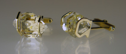Rare oil included quartz crystals in 9ct yellow gold - Cufflinks in 9ct yellow gold (smaller pair). Rare oil included quartz crystals from Balochistan are set in individually handmade gold mounts.  The crystals are approximately 2-3cm in all dimensions and contain golden droplets of light oil, along with darker bitumen and an aqueous solution.  The inclusions fluoresce a strong bluish green under UV light.  Each pair of cufflinks comes with a UV pen torch and an explanation of the crystal.  These crystals are extremely rare and it is difficult to find such perfect examples as sold by Just Gems.  The setting is precisely made to fit each unique crystal and has to be created without the application of heat, which could cause the crystal to fracture.  Each piece is handmade in Scotland and hallmarked in Edinburgh. Pendants and earrings also available.  A selection of crystals are available for bespoke designs.