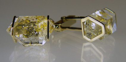Oil included natural quartz crystal cufflinks in gold - Cufflinks in 9ct yellow gold. Rare oil included quartz crystals from Balochistan are set in individually handmade gold mounts.  The crystals are approximately 2-3cm in all dimensions and contain golden droplets of light oil, along with darker bitumen and an aqueous solution.  The inclusions fluoresce a strong bluish green under UV light.  Each pair of cufflinks comes with a UV pen torch and an explanation of the crystal.  These crystals are extremely rare and it is difficult to find such perfect examples as sold by Just Gems.  The setting is precisely made to fit each unique crystal and has to be created without the application of heat, which could cause the crystal to fracture.  Each piece is handmade in Scotland and hallmarked in Edinburgh. Pendants and earrings also available.  A selection of crystals are available for bespoke designs.