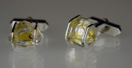 Oil quartz cufflinks in silver - Cufflinks in silver. Rare oil included quartz crystals from Balochistan are set in individually handmade gold mounts.  The crystals are approximately 2-3cm in all dimensions and contain golden droplets of light oil, along with darker bitumen and an aqueous solution.  The inclusions fluoresce a strong bluish green under UV light.  Each pair of cufflinks comes with a UV pen torch and an explanation of the crystal.  These crystals are extremely rare and it is difficult to find such perfect examples as sold by Just Gems.  The setting is precisely made to fit each unique crystal and has to be created without the application of heat, which could cause the crystal to fracture.  Each piece is handmade in Scotland and hallmarked in Edinburgh. Pendants and earrings also available.  A selection of crystals are available for bespoke designs.