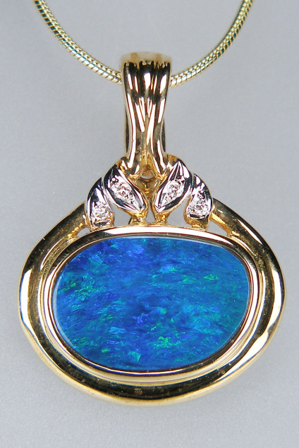 Opal doublet & diamond pendant with pearl enhancer clip fitting - Impressive bright blue with turquoise fleck, opal doublet, rubover set in 14ct yellow gold with diamond accents. The pandant hangs from a parl enhancer clip fitting enabling it to be worn with either a chain or with beads/pearls for a more dramatic appearance. Pendant measures 23 x 30mm. Chain not included