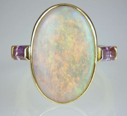 Opal & amethyst ring - 5.65ct oval opal with striking orange, green and violet colours set in 18ct yellow gold ring with amethyst baguette shoulders 
