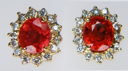 Ruby & diamond earstuds in 18ct yellow gold - Classic diamond halo earstuds with claws set stones. A 1.5ct fat oval pair of orangy coloured natural rubies with a halo of diamonds in 18ct yellow gold. The stone weights are estimated in the setting. These items are PRE-LOVED, the gemstones have been tested and verified by Just Gems.