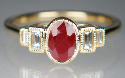 Ruby & diamond ring in 9ct yellow gold - Oval ruby - included natural heat treated but NOT glass filled - weighing 1.13ct and flanked by two pairs of baguette cut diamonds, total diamond weight is 0.18ct, the stones are all rubover set in 9ct yellow gold. Ring is size O and can be resized. 