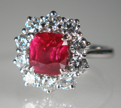Ruby & diamond cluster ring in platinum - Rectangular cushion cut natural and unheated ruby weighing 2.53ct, surrounded by a halo of 10 round brilliant cut diamonds each 3.3mm in diameter in E colour VS clarity. The ruby is accompanied by a report  confirming that it is natural, with no evidence of heat treatment and that the origin opinion is East Africa. The total diamond weight is 1.49ct. Ring is in platinum. 
