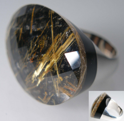 Rutilated quartz ring in silver - Dramtic ring made of a harlequin faceted cabochon rutilated quartz set on a black onyx back, mounted on a silver shank. This unique peice is fingersize O and cannot be resized. The rutilated quartz is 31 x 23mm oval. The ring is included in our 20 year anniversary 50% sale andd now costs £120.