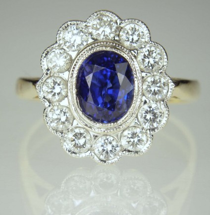 Sapphire & diamond ring in 18ct gold - Second hand (customer trade-in) sapphire & diamond cluster ring.  Nice quality central oval sapphire of approximately 1.25ct is surrounded by 0.5ct of round brilliant cut white diamonds.
