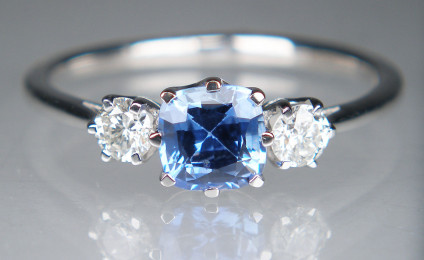 Sapphire & diamond ring in platinum - Dainty sapphire & diamond ring in platinum set with a 0.73ct cushion cut mid blue natural sapphire, flanked by a 0.24ct pair of G colour VS clarity round brilliant cut diamonds. The gems are all claw set in platinum. Ring size is N