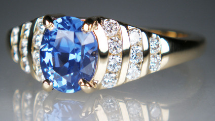 Sapphire & diamond ring in 18ct yellwo gold - A lady’s dress ring in 18ct yellow gold with a 2.10ct oval cut UNHEATED natural blue sapphire, from Sri Lanka, set with 0.51ct of round brilliant cut diamonds in G colour VS clarity. The sapphire is claw set, the diamonds are channel set. 