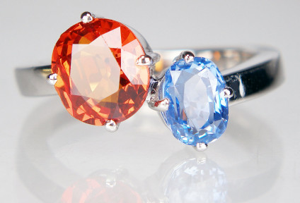 Orange and blue sapphire twist ring in 18ct white gold - Unheated natural orange sapphire from Madagascar weighing approximately 2ct and set with an oval blue sapphire of about 70pts in 18ct white gold. This item is pre-loved. 