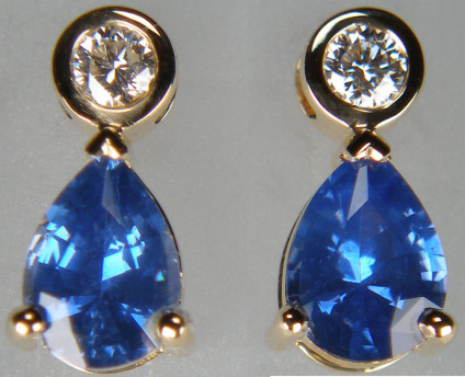 Sapphire & diamond earrings in 18ct yellow gold - Bright and sparkly blue sapphire pair of pear cuts weighing 1.54ct, suspended from rubover set round brilliant cut diamonds in F colour SI clarity 0.17ct total diamond weight in 18ct yellow gold earrings