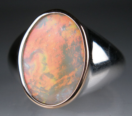 White opal ring in silver  - Fiery orange/green flashing white opal rubover set in 9ct rose gold on silver ring. Ring is size O. Opal is 18 x 13mm.